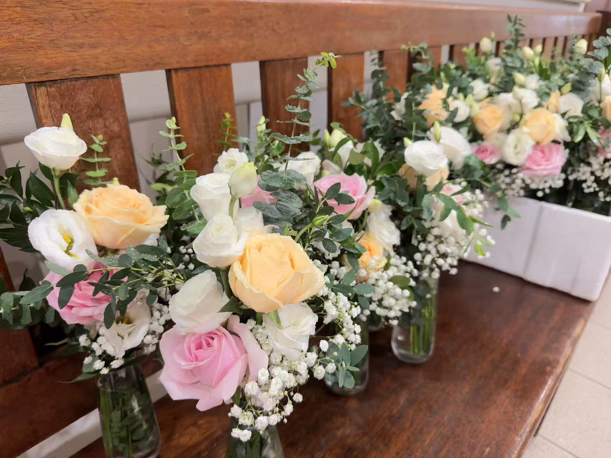 Close-up of pastel roses, lisianthus, baby's breath, and eucalyptus in glass vases