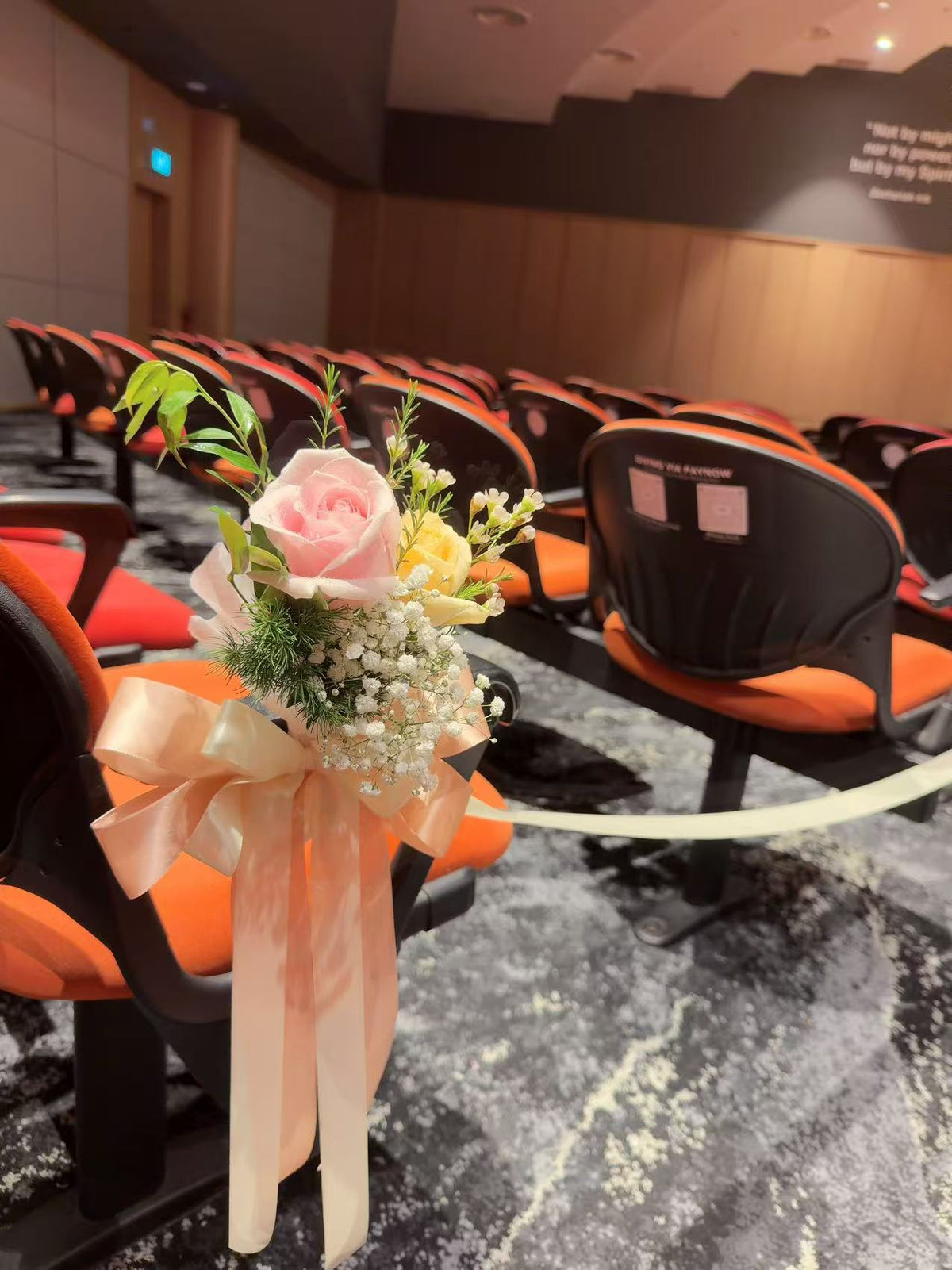 Close-up of pew posy featuring pink and yellow roses with baby's breath