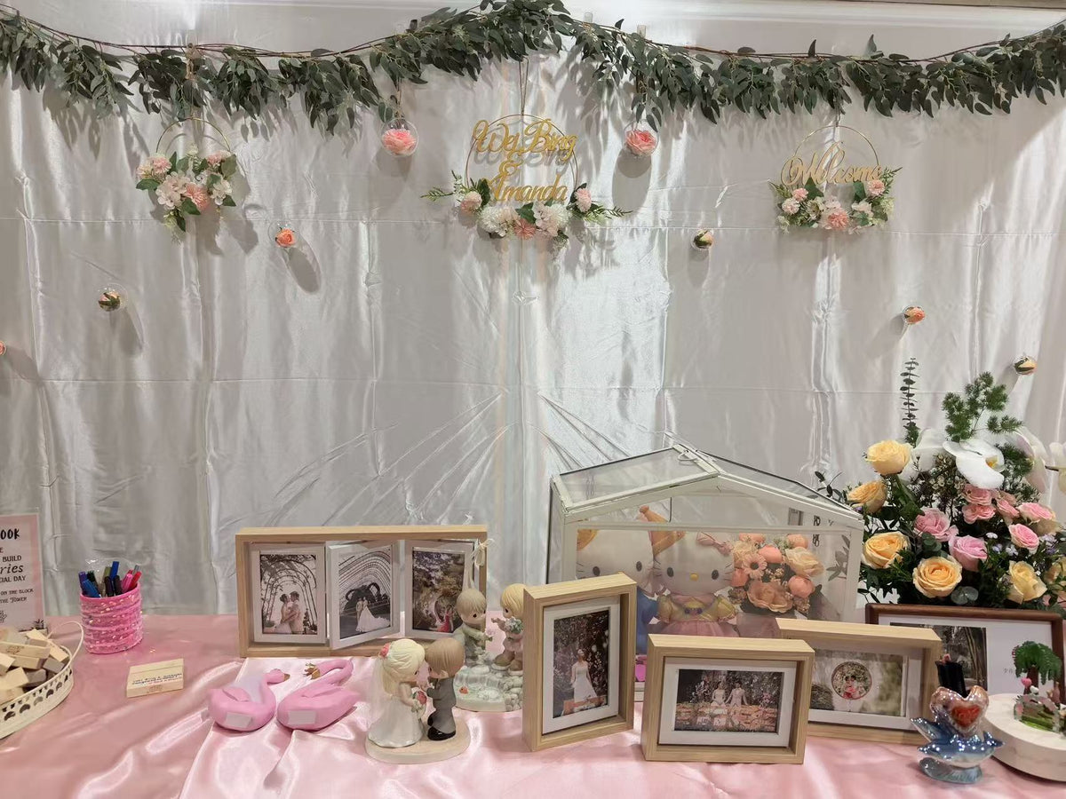 Draped photo memory table with gold frames, terrarium, and background floral hoops