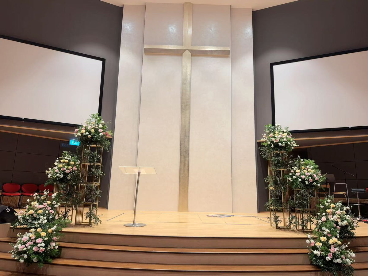 Full stage view framed by gold multi-tiered floral pedestals