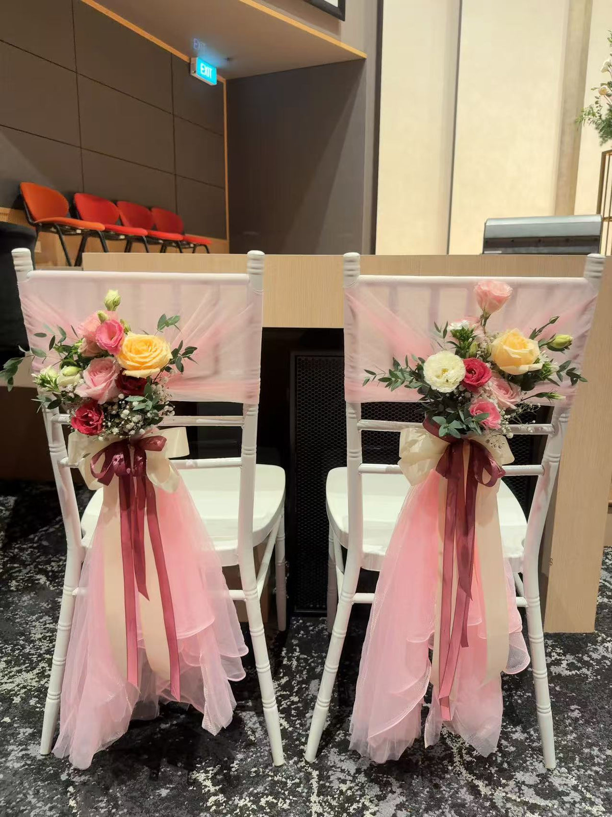 White Tiffany seats styled with pink tulle, burgundy ribbons, and fresh floral tie-backs