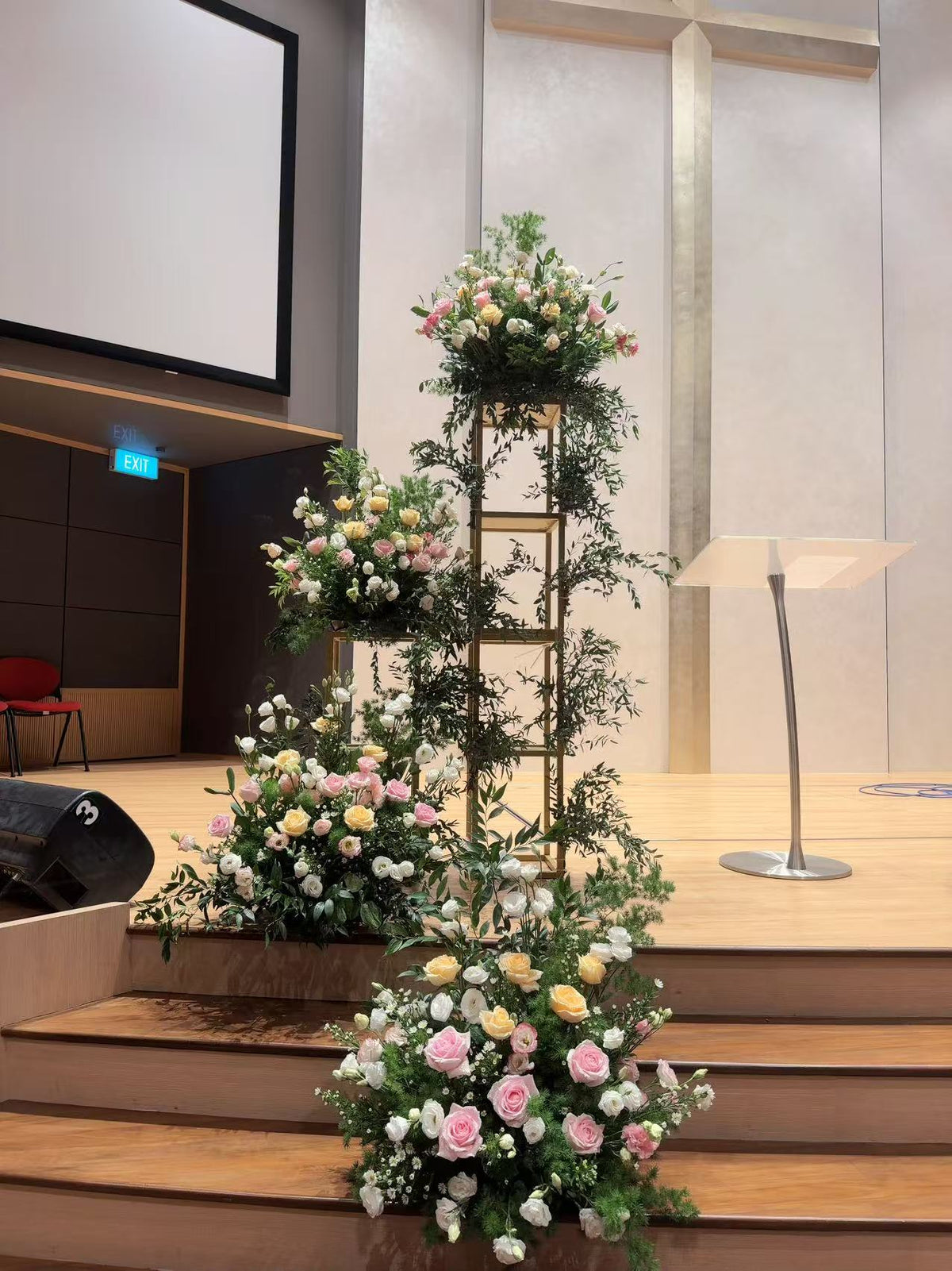 Side close-up of multi-level gold pedestal with cascading pastel floral arrangements