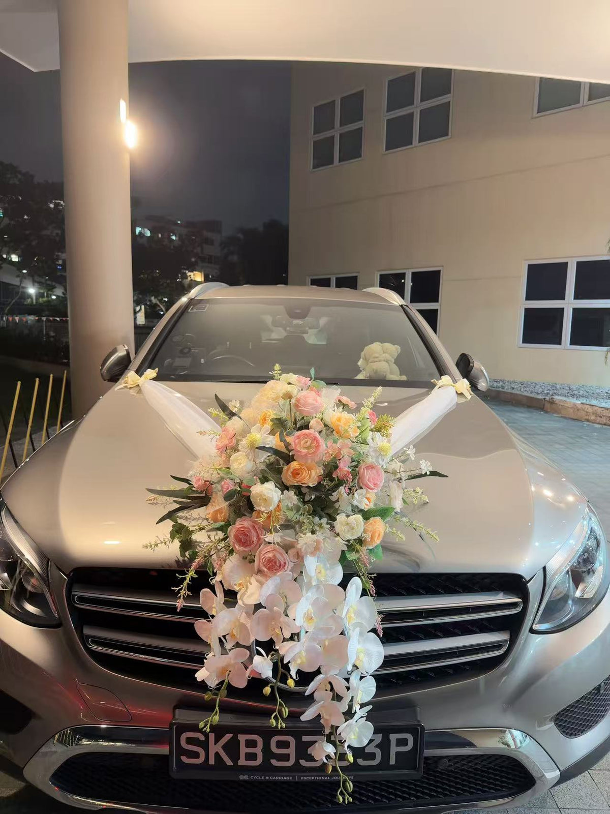 Front view of silver bridal car featuring cascading white orchids and pastel roses